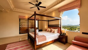 A four-poster bed with a view of the landscape through a window.