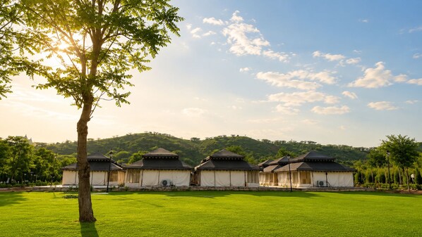 A row of traditional-style buildings with a flat roof and a central pavilion, surrounded by a well-maintained lawn.