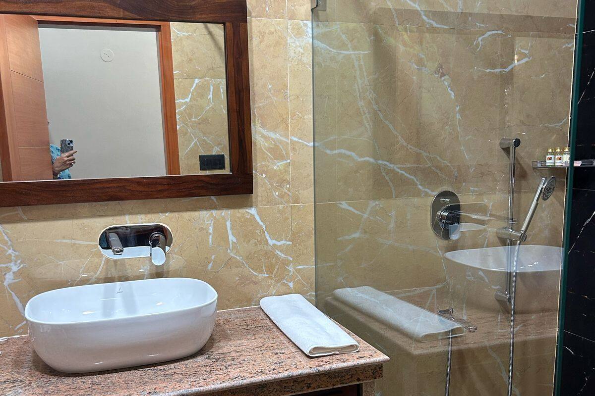 A bathroom with a marble vanity, a sink, a mirror, and a glass-enclosed shower area.