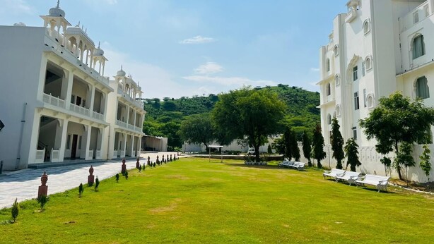 A courtyard with white buildings, a central lawn, and trees. - Roop Garh Palace (Jamwa Ramgarh)