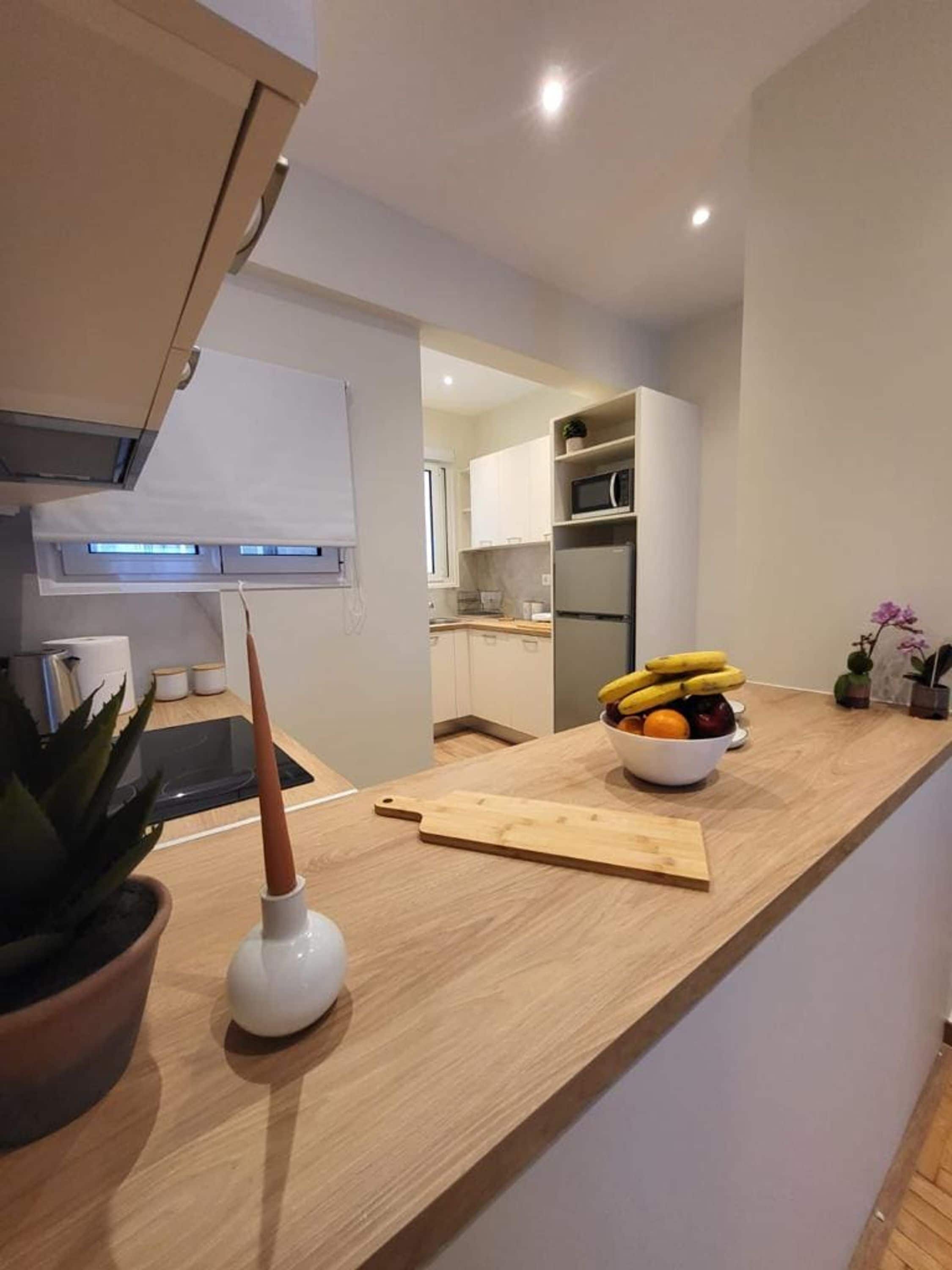 A modern kitchen with a wooden countertop, a bowl of fruit, and a potted plant.