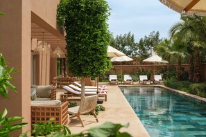 A poolside area with lounge chairs, umbrellas, and a well-maintained garden. - TY HABIBI (Marrakech)