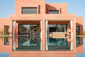 Een modern gebouw met grote glasramen, een zwembad en een eetgedeelte met terras.