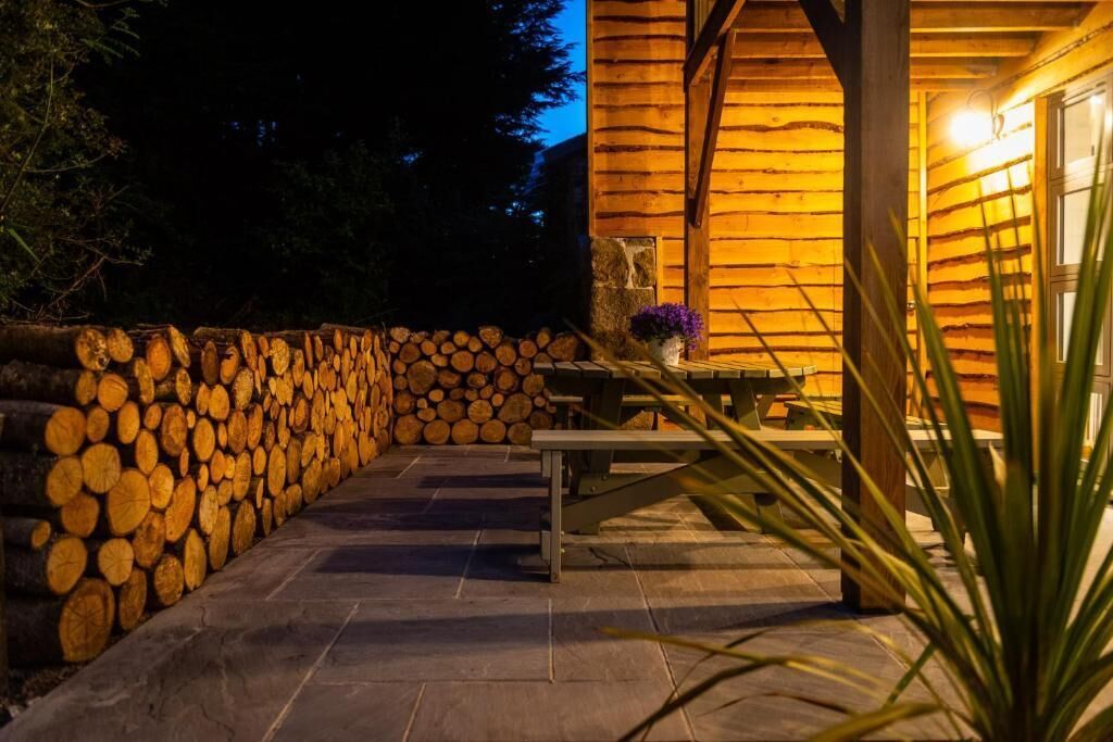 A wooden cabin with a stone wall and stacked logs.