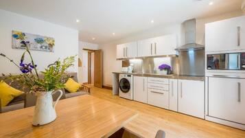 A modern kitchen with white cabinets, a stainless steel range hood, and a built-in oven.