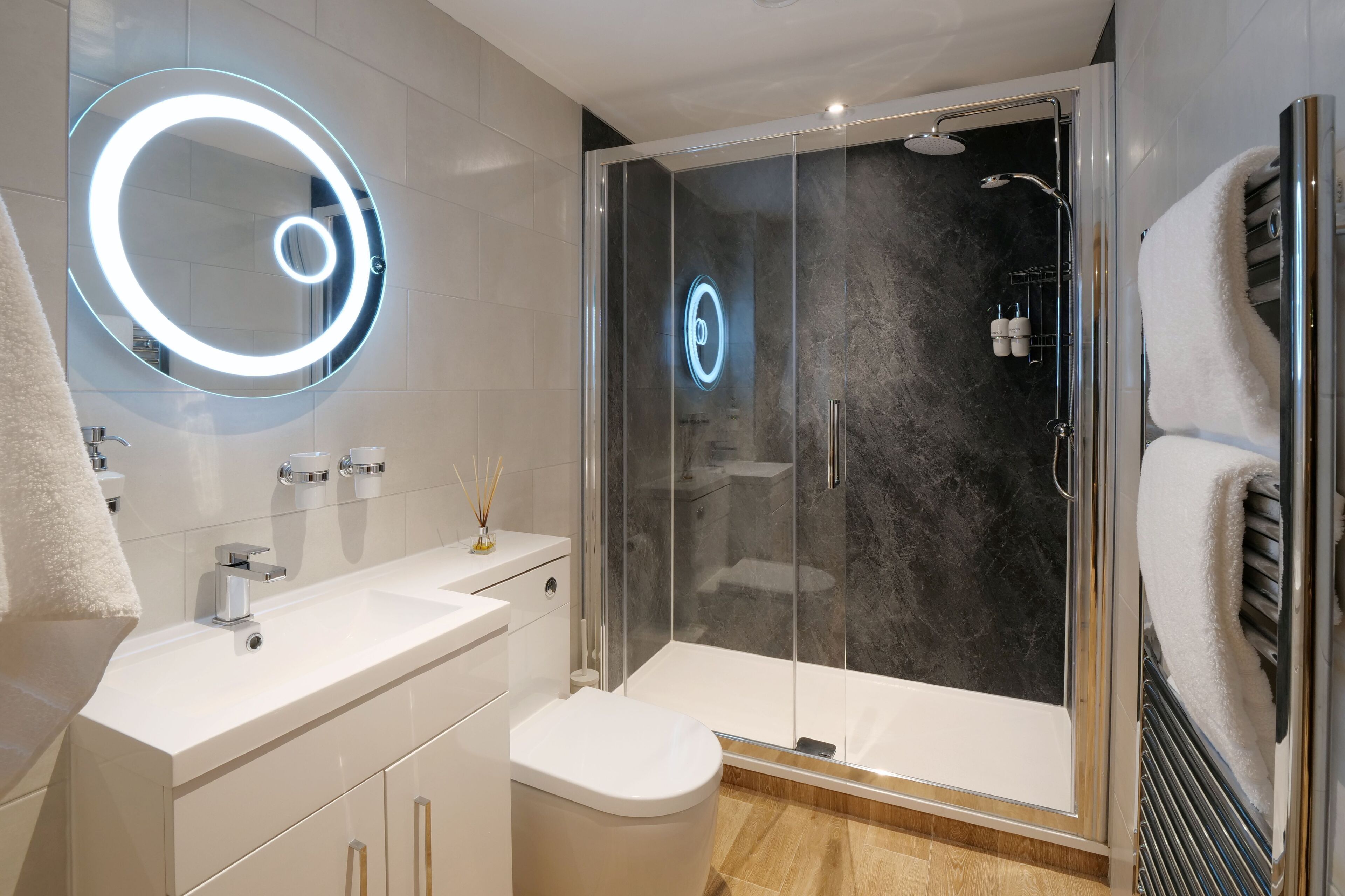 A modern bathroom with a glass-enclosed shower, a vanity with a mirror, and a toilet.