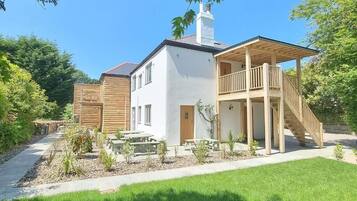 Een modern herenhuis met twee verdiepingen, een balkon, een houten schutting en een verzorgde tuin.