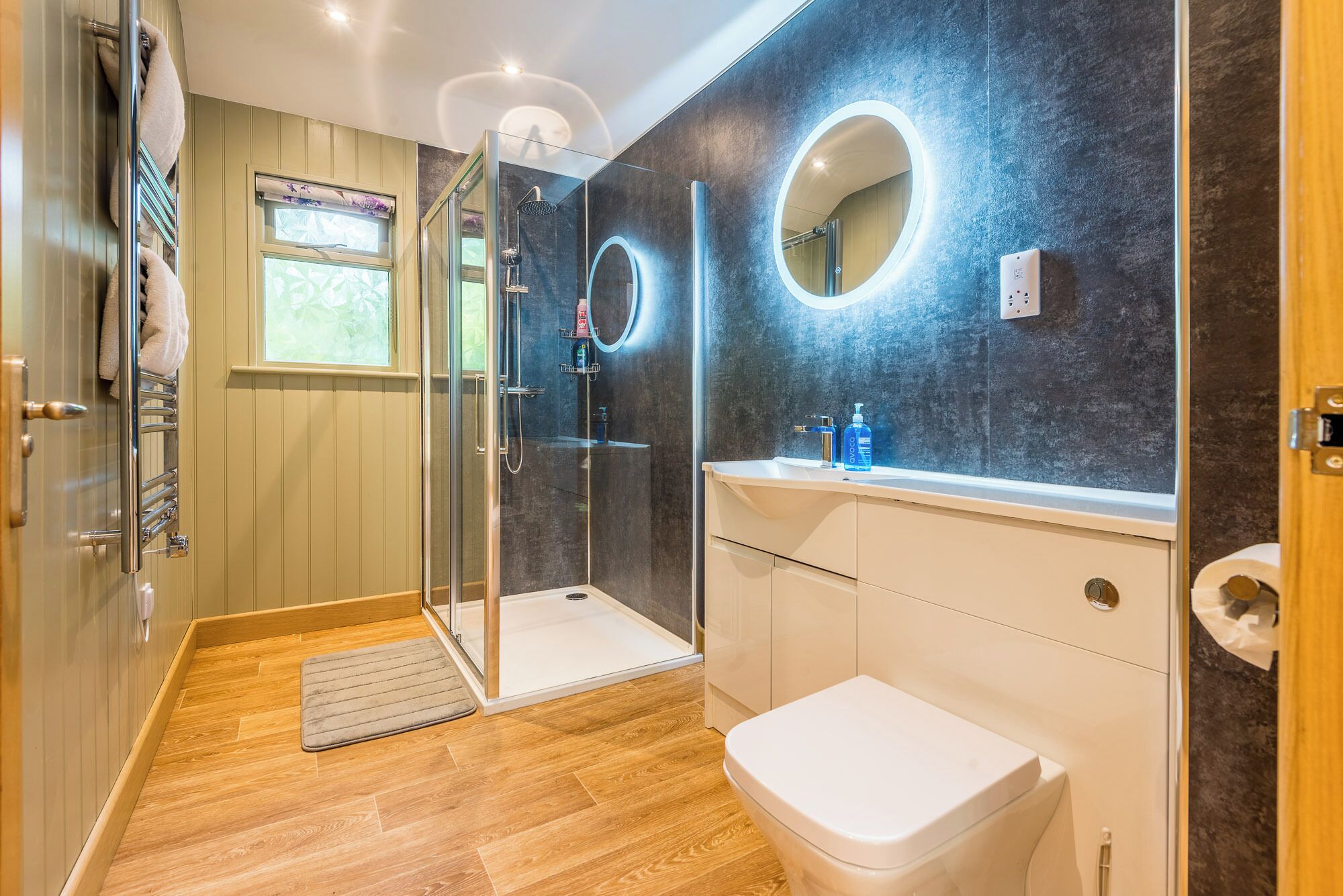 A modern bathroom with a glass shower enclosure, a white toilet, and a vanity with a mirror.