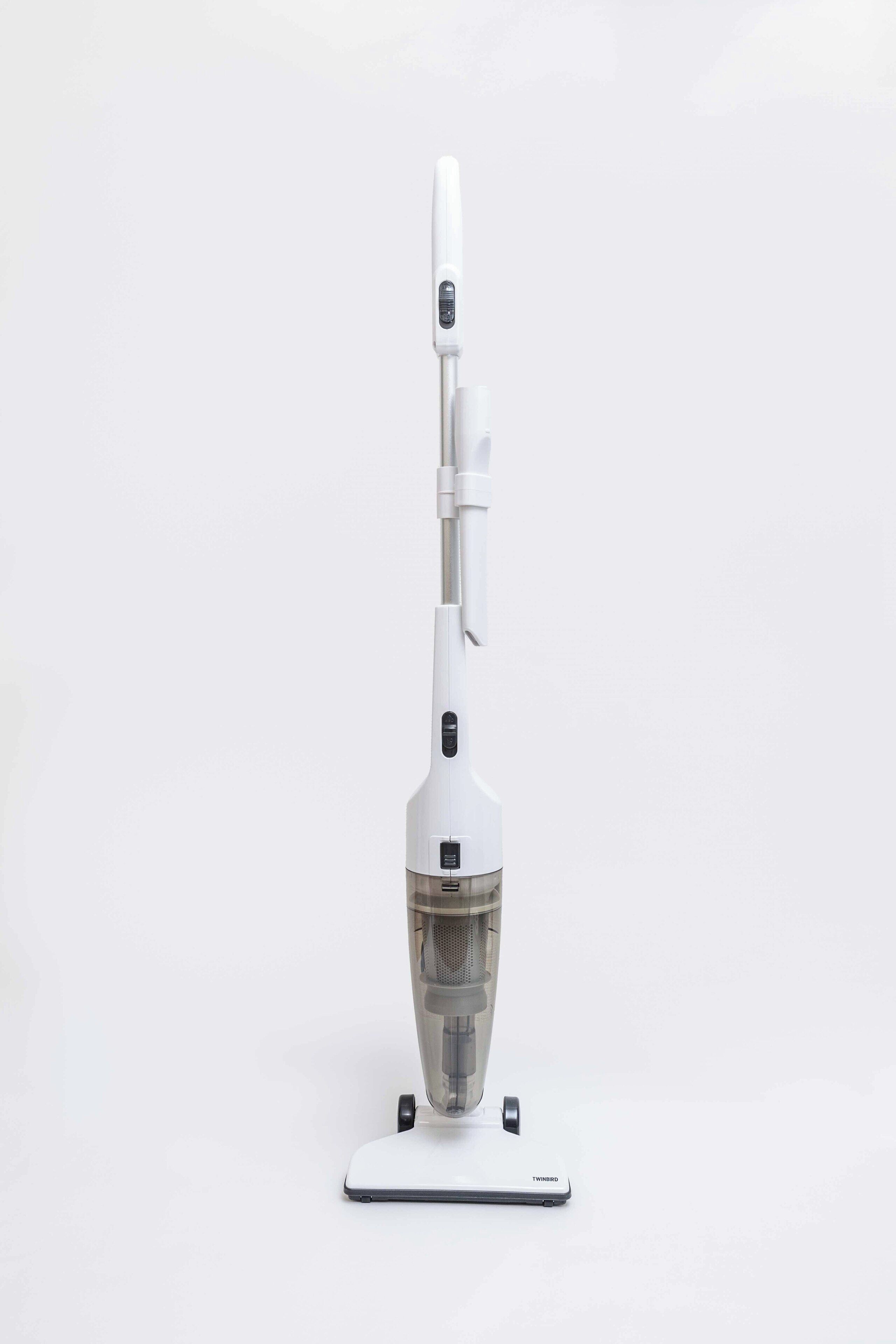 A white, modern, portable vacuum cleaner with a transparent dust container, a control panel, and a base with wheels.