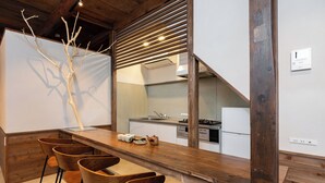 A modern kitchen with a wooden bar and bar stools. - Mameyama15 (Nara)