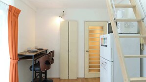 A compact kitchen with a refrigerator, a microwave, and a wooden ladder. - Sakura Yoyogi by Tranova (Tokyo)