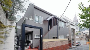 A residential building with a brick facade, a visible entrance, and a car parked in the driveway. - Sakura Yoyogi by Tranova (Tokyo)