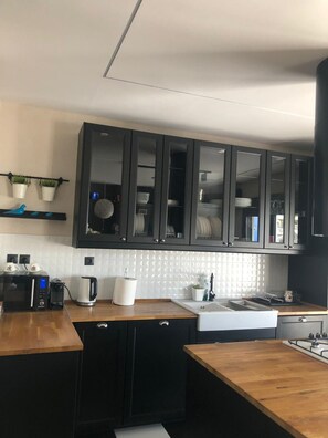 Eine moderne Küche mit dunklen Schränken, einer Holzarbeitsplatte, einem eingebauten Ofen und einer Spüle.