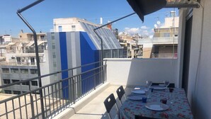 A balcony with a table set for dining, chairs, and a railing. - Luxurious Apartment With big Balcony Best Location (Athens)