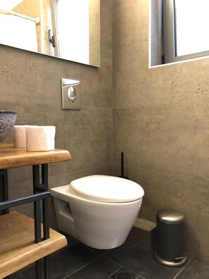 Ein modernes Badezimmer mit Toilette, Mülleimer und Handtuchspender.