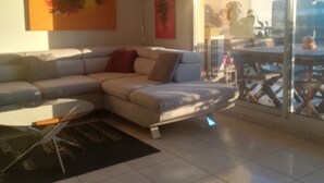 Uma sala de estar moderna com um sofá seccional, uma porta de vidro que dá para um pátio externo e obras de arte nas paredes.