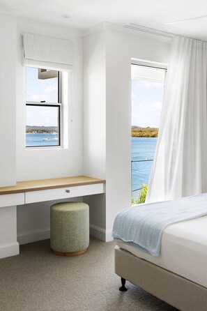 Een slaapkamer met een bed, een bureau, een raam met uitzicht op zee en een uitzicht op de lucht.