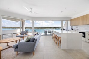 Een moderne keuken met een groot schiereiland, barstoelen en uitzicht op zee.
