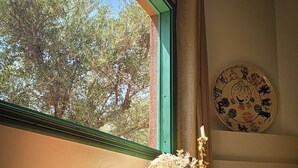 A table with a vase of dried flowers, a candle, and a patterned container by a window with a view of trees. - Maison Chaliya guesthouse  (Tamazouzte)