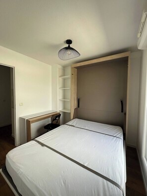 Cozy retreat with a single bed, desk, and shelving unit.