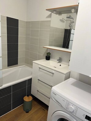 Bathroom features a bathtub, sink, mirror, and washing machine.