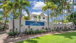 A sign for The Port of Palm Beach Queensland with a white building in the background.