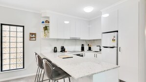 A modern kitchen with white cabinets, a marble countertop, and a built-in refrigerator.