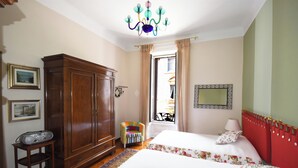 Una camera da letto con due letti, un armadio, una sedia e un lampadario.
