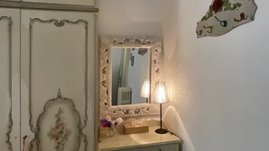 Una stanza con un mobile toilette, uno specchio con cornice elaborata, una lampada e una decorazione floreale al muro.