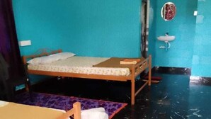 Quarto com duas camas de madeira, uma mesinha, pia e espelho.