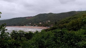 Un paisaje costero con playa, colinas y edificios al fondo.