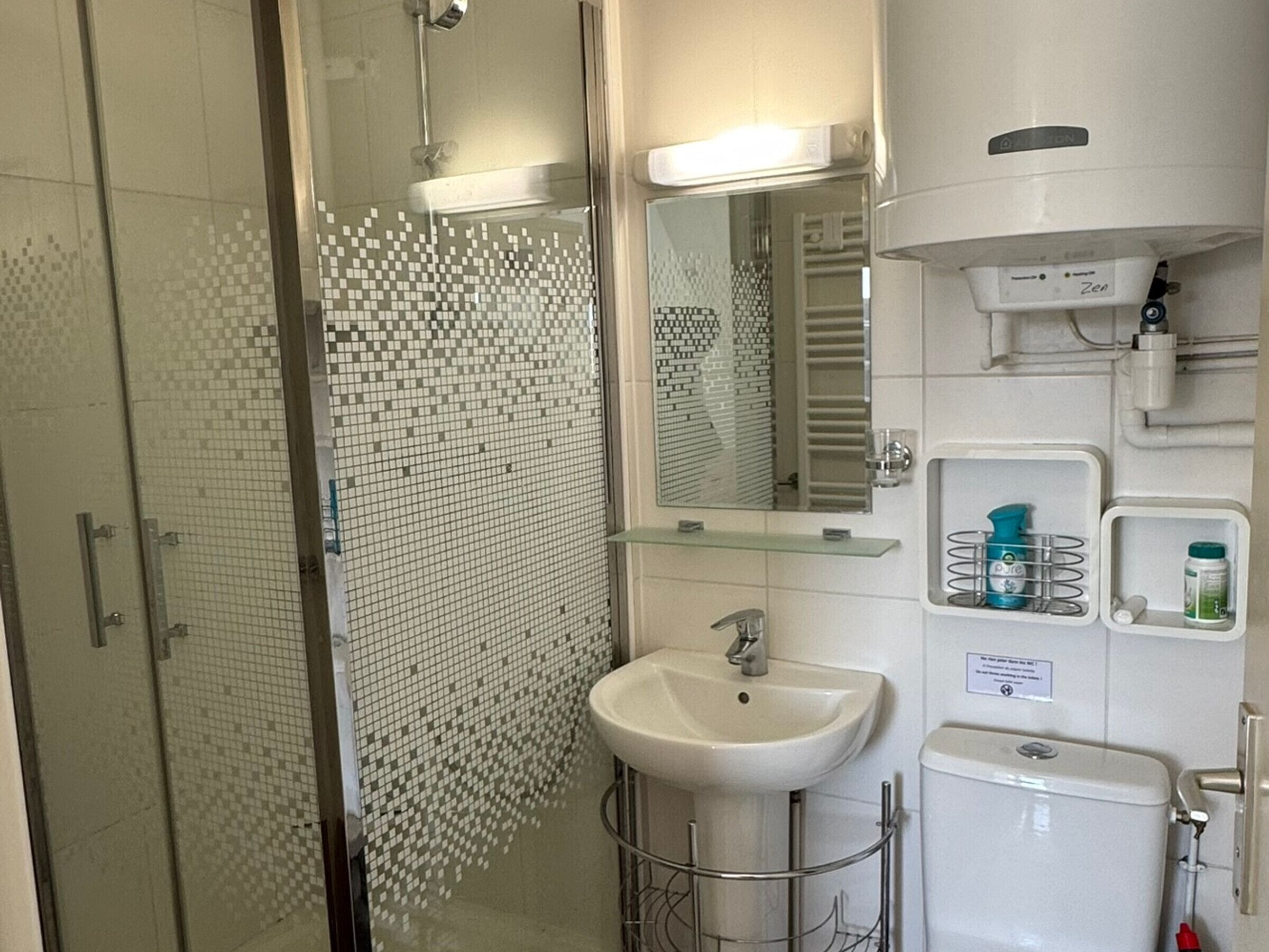 A modern bathroom with a glass shower enclosure, a white sink, a mirror, and a toilet.