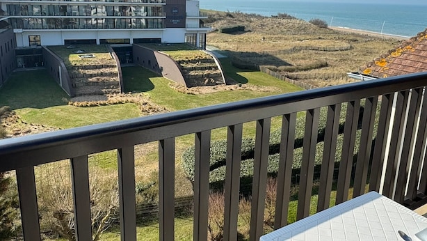 Ein modernes Gebäude mit Flachdach und großen Fenstern, das auf eine Küstenlandschaft mit freiem Blick auf das Meer blickt.