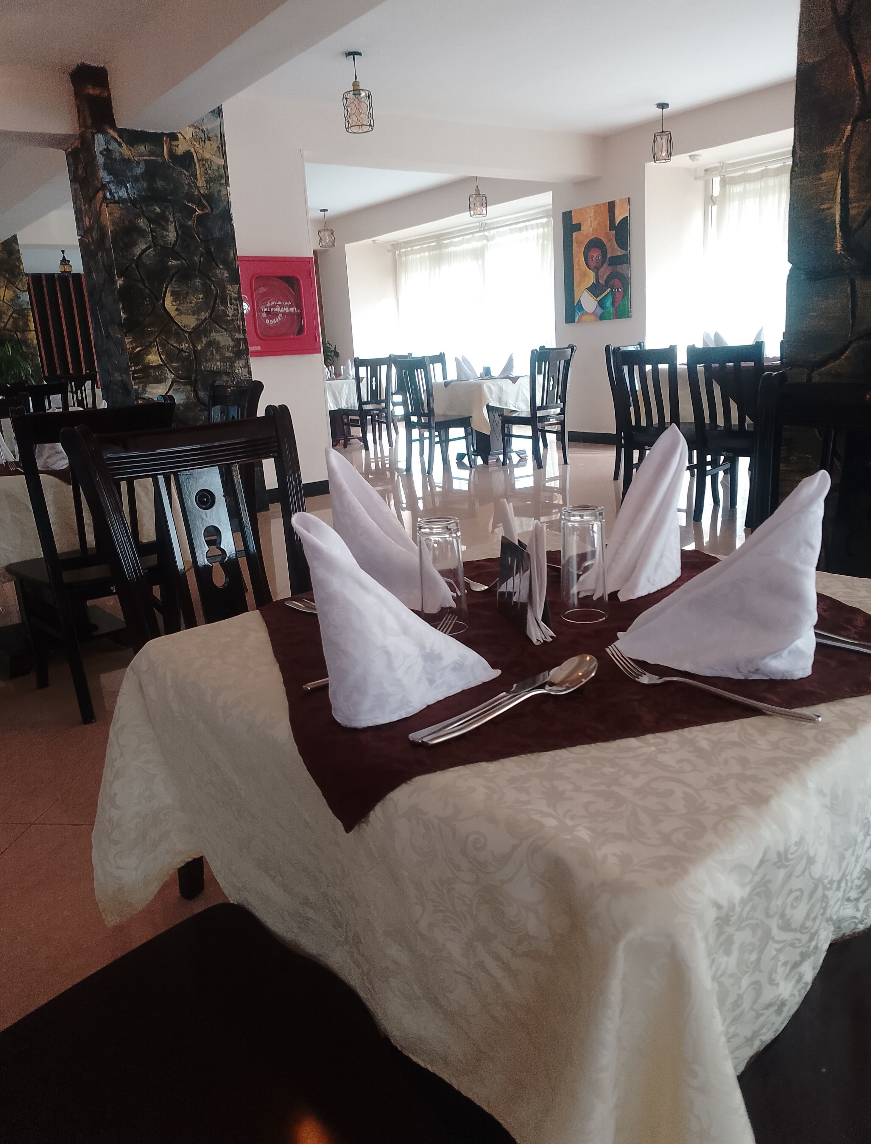 A dining area with a table set for four, featuring white napkins, cutlery, and glasses.