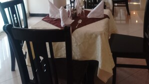 Uma sala de jantar com mesas preparadas para o serviço, cadeiras e obras de arte nas paredes.