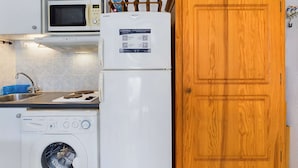 Une cuisine compacte équipée d’un four à micro-ondes, d’un réfrigérateur et d’un lave-linge.