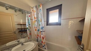 A bathroom with a sink, mirror, and bathtub.