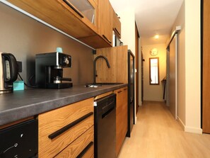 Una cocina compacta con armarios de madera, una cafetera, un fregadero y un lavavajillas.