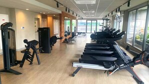 Un gimnasio con cintas de correr, máquinas de pesas y un espejo.