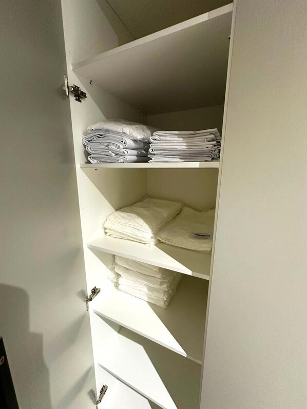A white wardrobe with multiple shelves, each holding neatly folded white towels.
