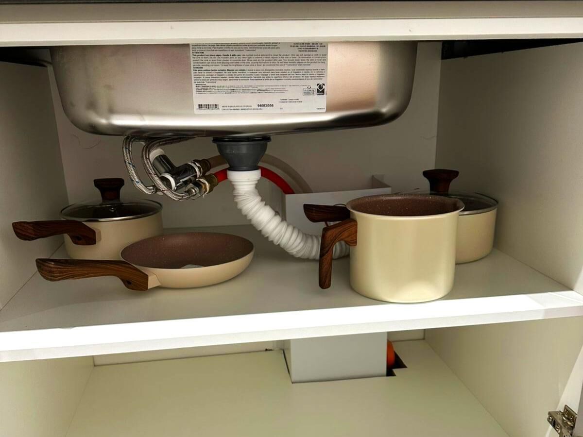 A kitchen shelf with cookware, including a frying pan, a pot, and a saucepan.