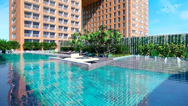 Una piscina con agua cristalina, rodeada de vegetación y edificios modernos.