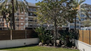 Une piscine entourée d’une clôture en bois, avec un arbre et un bâtiment en arrière-plan.