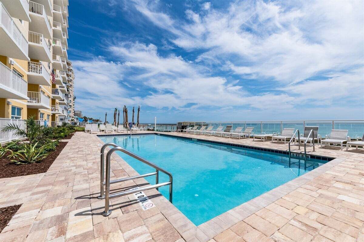 Une piscine avec un ciel bleu dégagé et une vue sur l’océan.
