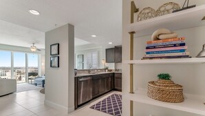 Een moderne keuken met roestvrijstalen apparatuur, een eethoek met uitzicht en een boekenplank vol reisboeken.
