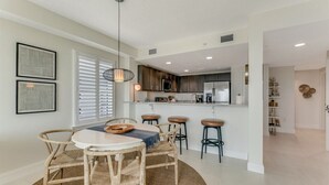 Een moderne keuken met witte kastjes, een centraal eiland en barstoelen.