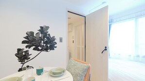 A room with a bed, a dining table with plates and glasses, a chair, and a plant. - RIZOTIA HAKUSAN by Tranova (Tokyo)