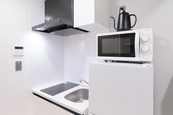 A modern kitchen with a built-in microwave, a coffee maker, and a stainless steel sink. - RIZOTIA HAKUSAN by Tranova (Tokyo)