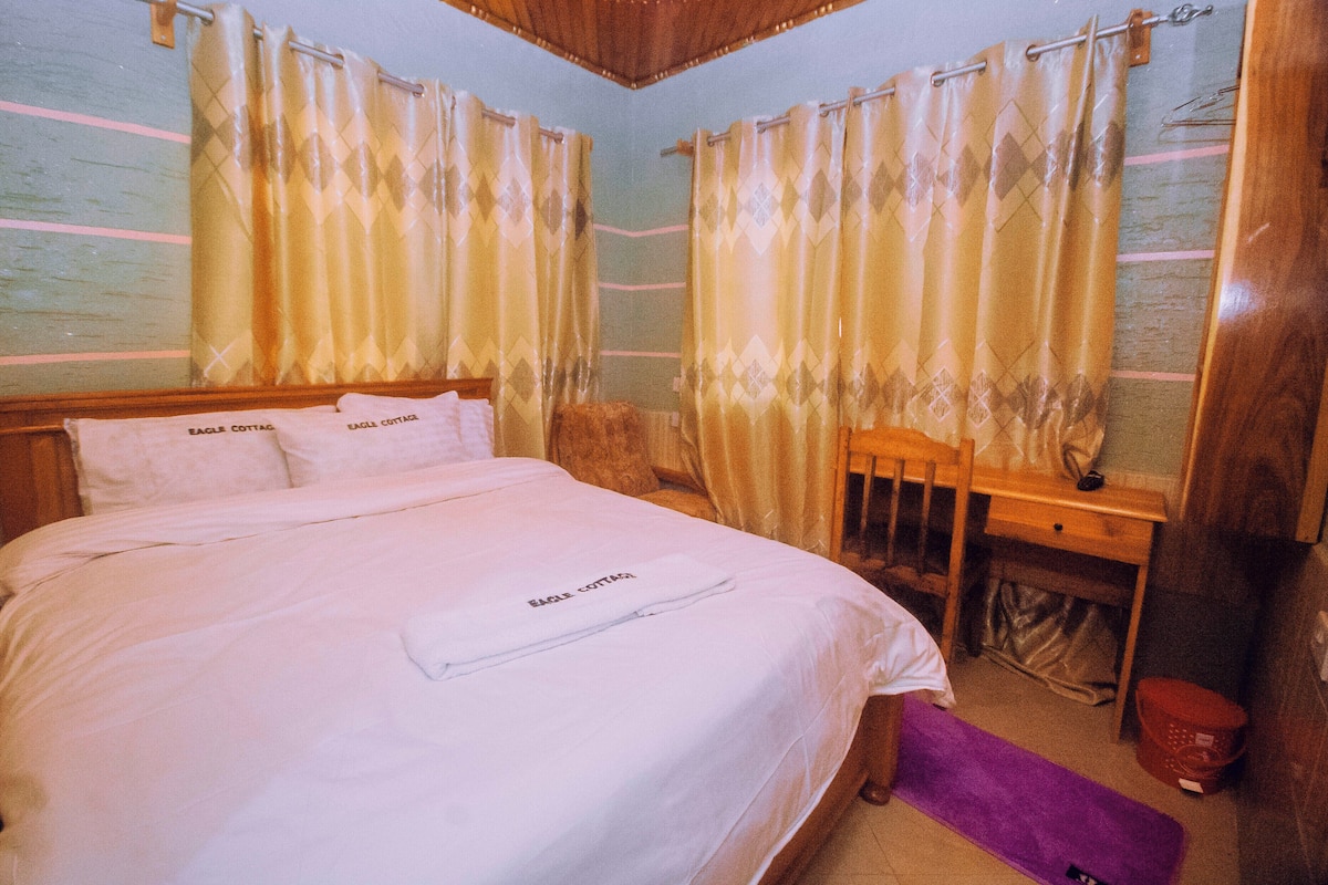 Un dormitorio con una cama grande, cabecera de madera y cortinas.