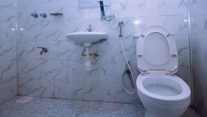 Un baño con inodoro blanco, lavabo y ducha.